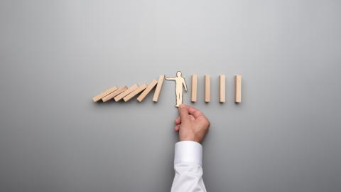 des dominos qui tombe sont retenus par une figure humaine